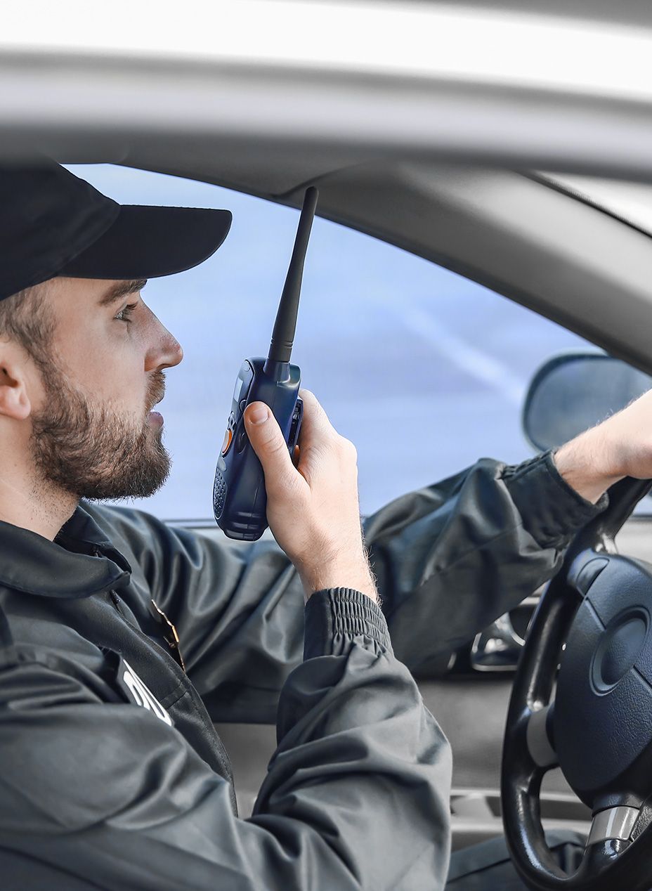 Eximm security guard communicating via handheld 2-way-radio in front of a retail shopping centre in Pimpama, Gold Coast, QLD, Australia. 